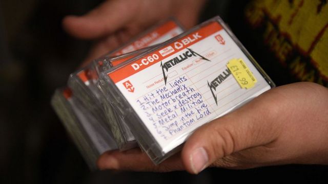 An employee of the music shop 'Record Collector' holds copies of Metallica's reissued 1982 demo tape in 2015