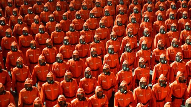 游行队伍中出现一部分人身穿红色的防化套装和戴防毒面具引起外媒关注。(photo:BBC)