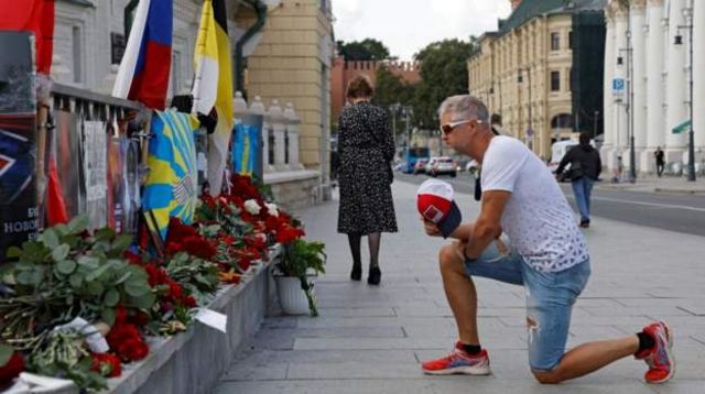 Homem se ajoelha diante de flores em homenagem a Prigozhin
