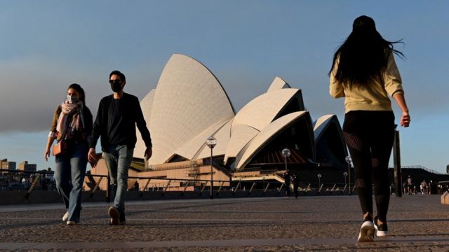 Pessoas usando máscaras caminham pela Sydney Opera House durante um lockdown em todo o estado em agosto de 2021