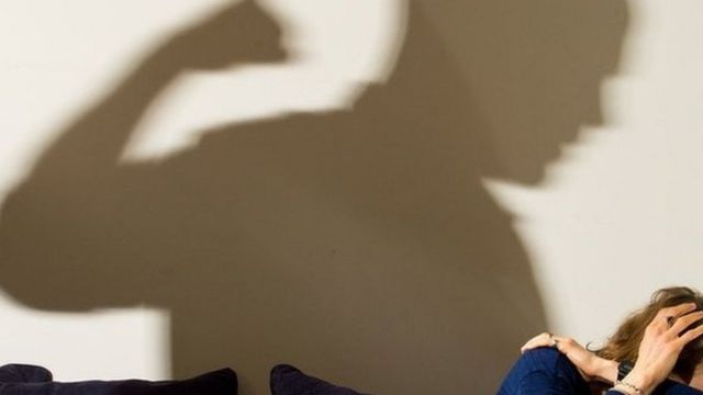 Generic image suggesting domestic violence with a shadow of a man raising his fist behind a woman cowering on a sofa