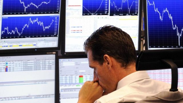 Un hombre frente a pantallas que muestran la fluctuación de acciones en la bolsa de valores