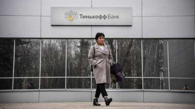 Una mujer camina frente a una sede del Banco Tinkoff.