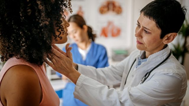 Médica examina pescoço de mulher