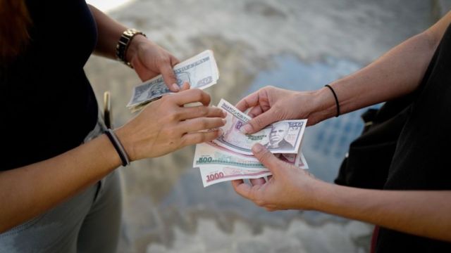 Personas intercambiando billetes de pesos cubanos.