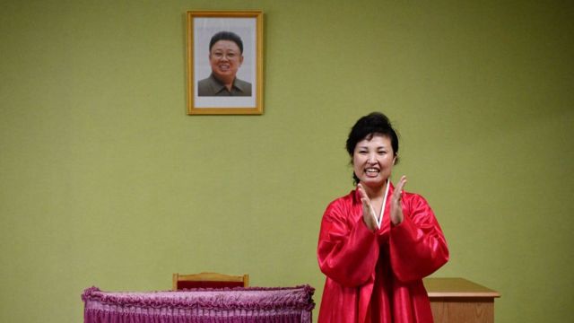 Norcoreana aplaudiendo frente al retrato de Kim Jong-il.