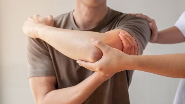 Un professionnel de la santé vérifie le coude d'un homme.