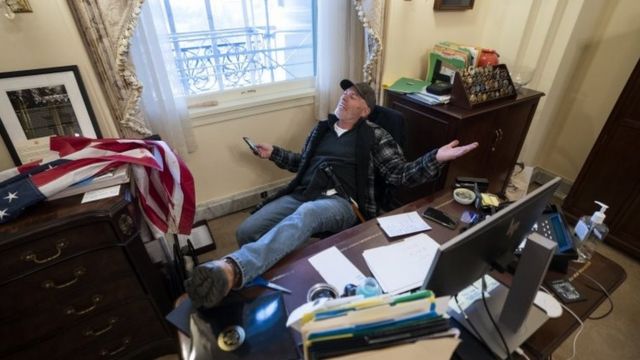 A rioter with feet on desk