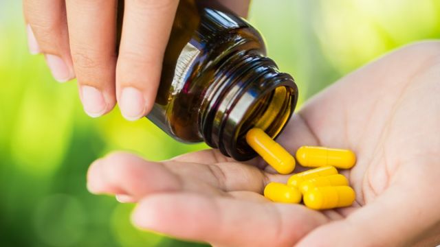 Mulher despeja comprimidos na palma de uma das mãos