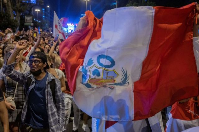 Un grupo de personas porta una bandera de perú