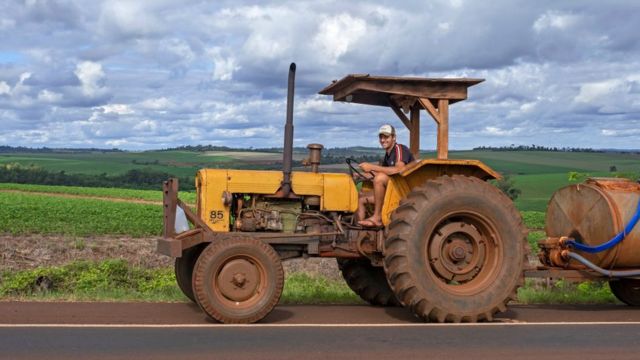 Trabajador rural sobre un tractor en campos de agricultura en Paraguay.