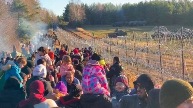 Migrants near a barbed wire fence