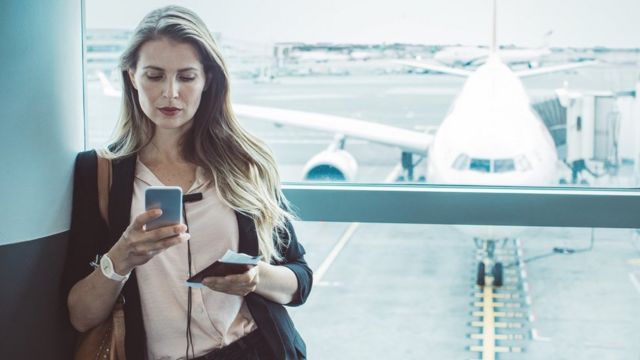 Une femme utilisant son téléphone dans un aéroport.