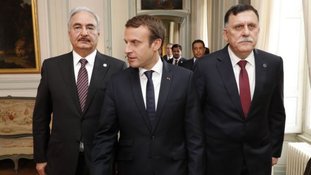 French President Emmanuel Macron (C) walks with Libyan Prime Minister Fayez al-Sarraj (R) and General Khalifa Haftar (L), commander in the Libyan National Army (LNA),