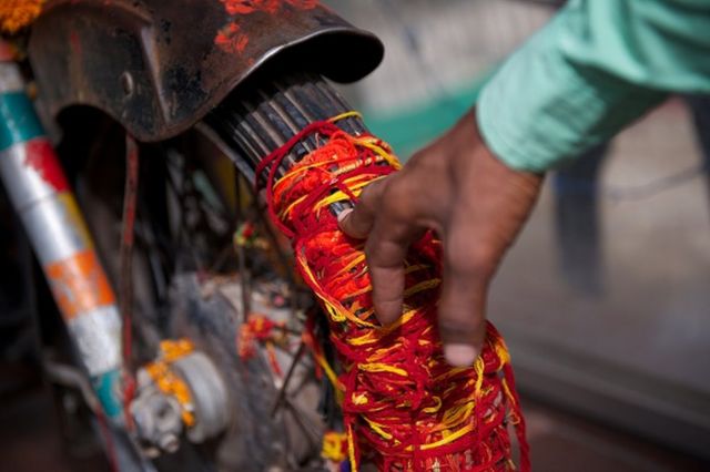 بعض المصلين يربطون خيطاً حول الدراجة النارية في معبد "بوليت بابا" في جودبور بالهند في 16 يوليو/تموز 2016. ورغم أن اسم المعبد هو "أوم بانا"، إلا أنه يشتهر باسم "بوليت بابا"، أو القديس بوليت