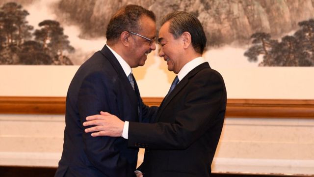 Tedros Adhanom, directeur général de l'Organisation mondiale de la santé, (G) serre la main du conseiller d'État et ministre des affaires étrangères chinois Wang Yi