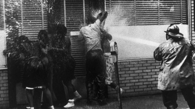 Manifestantes negros siendo rociados con agua por los bomberos.