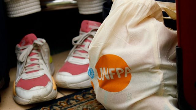 Los zapatos de una mujer junto a la bolsa del kit de dignidad con el logo del UNFPA