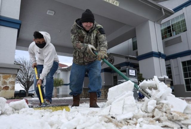 Duas pessoas retiram neve da entrada de casas no Texas