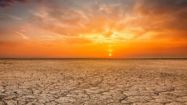 Puesta de sol en el horizonte y un terreno quebrado durante una sequía