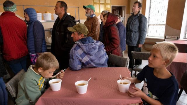 Seven-year-old Nikita and her 8-year-old brother Yegor eat lunch at a newly opened soup kitchen in the recently liberated Ukrainian city of Izium.  Many local shops and businesses were destroyed.