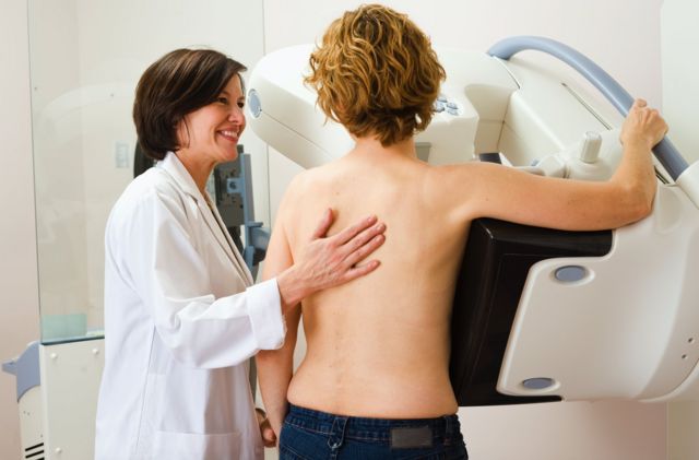 Médica ajudando mulher a fazer mamografia