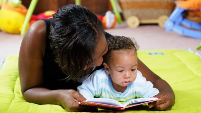 Madre leyendo un libro con su hija pequeña.