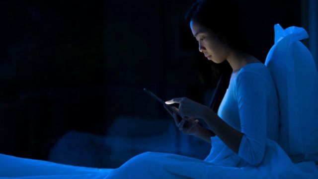 Jovem mexe em tela sentada na cama