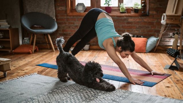 Uma mulher exercitando na companhia de seu cachorro.