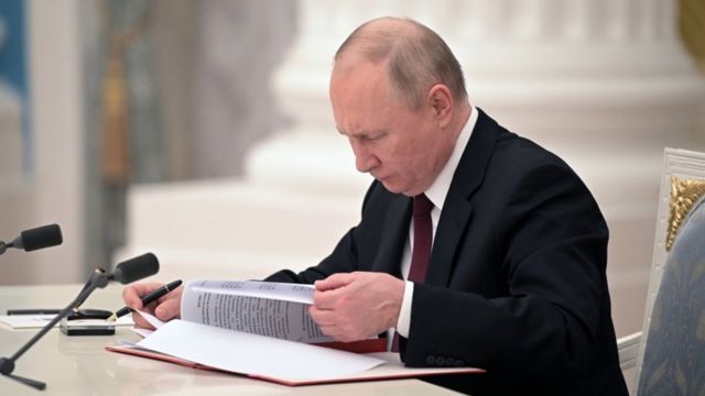 Putin sentado, olhando para livro