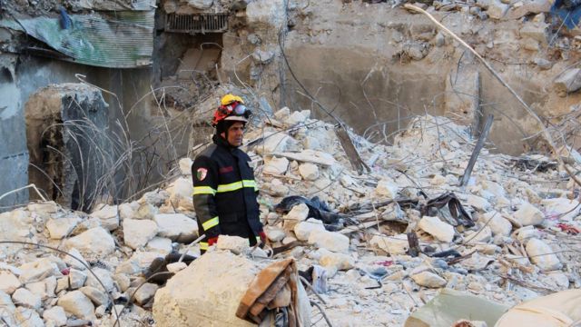 Un rescatista observa desconsolado las ruinas de un edificio.