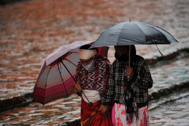 पानी पर्दा छाता ओढेर हिँडिरहेका महिलाहरू