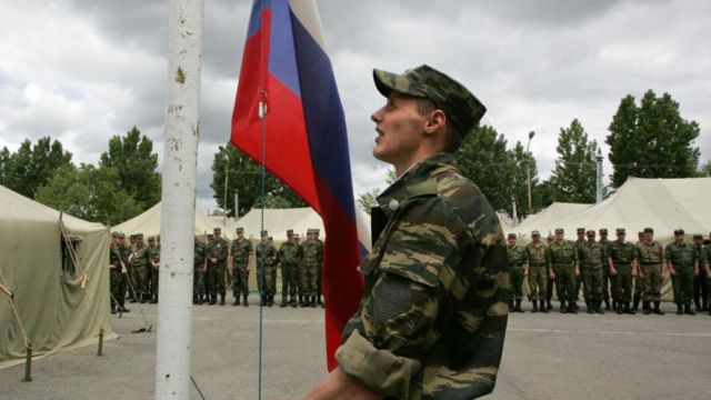 Российский солдат поднимает флаг России в 