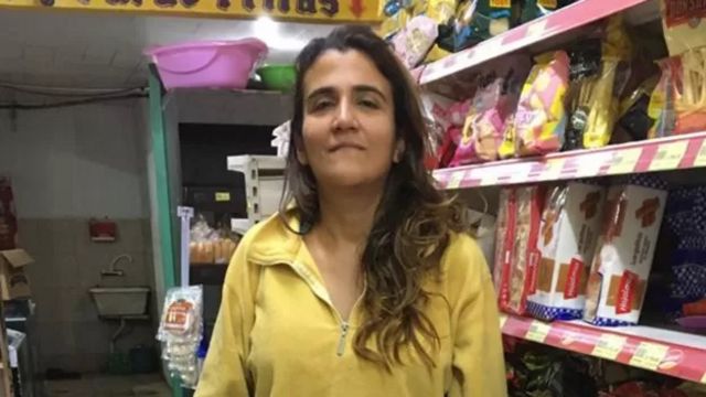 Mulher branca em frente a prateleira de mercado