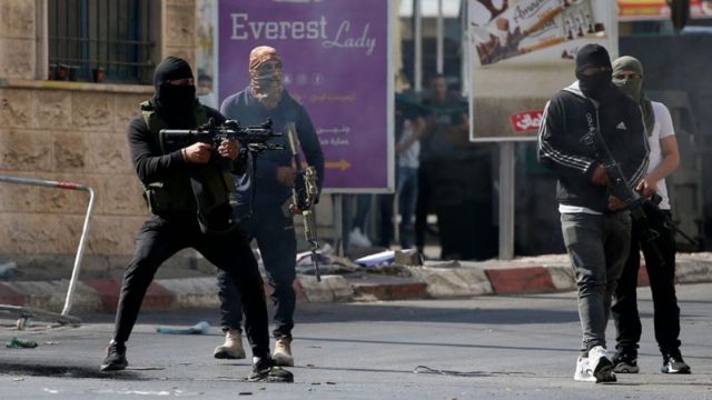 Militantes palestinos com rostos cobertos e armas em punho
