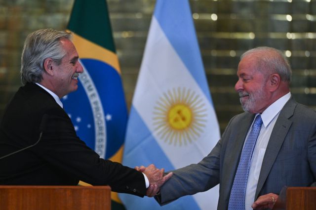 Alberto Fernandez e Lula apertando as mãos e sorrindo em frente às bandeiras do Brasil e Argentina, speaks alongside the President of Brazil, Luiz Inacio Lula da Silva, 