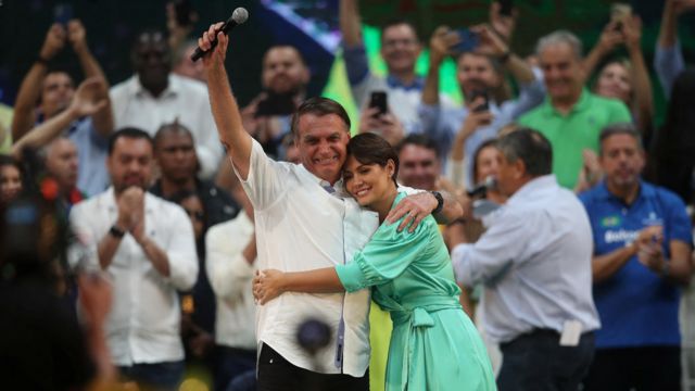 Jair Bolsonaro e Michelle Bolsonaro abraçados em evento de campanha