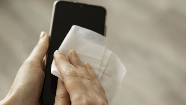 Mão de pessoa limpando tela de celular