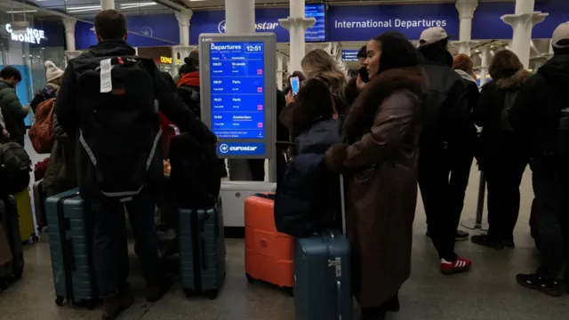 Passengers wait with suitcases at St Pancras as Eurostar trains are cancelled