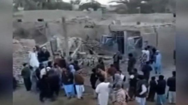 A crowd of people surround debris after an attack