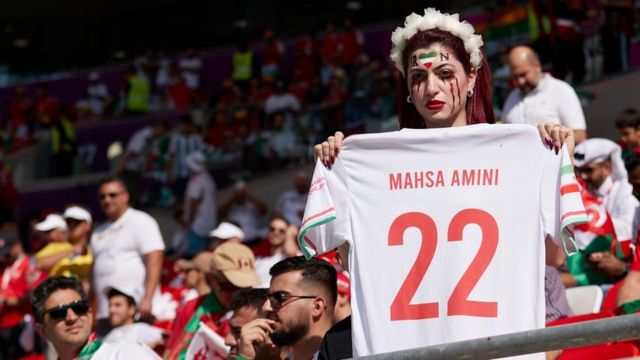 An Iranian fan holds a T-shirt bearing the name of Mahsa Amini before Iran's match against Wales