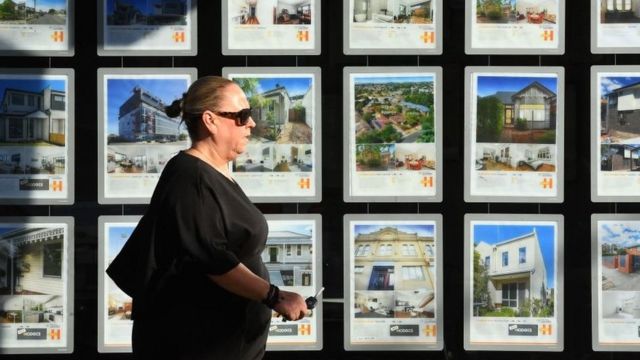 Woman walks in front of several real estate ads