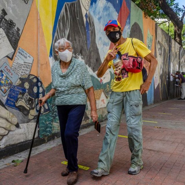 Una mujer adulta mayor caminando junto a un joven en Caracas.