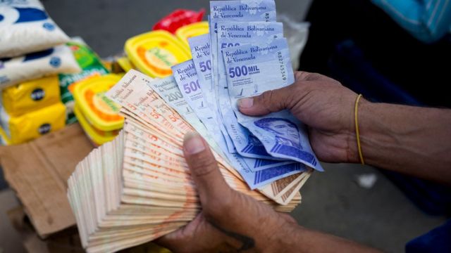 Un hombre sostiene billetes de bolívar en un mercado callejero en el distrito de Catia de Caracas el 6 de abril de 2021, en medio de la pandemia de COVID-19.