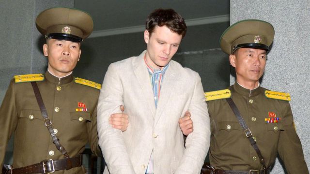 Otto Warmbier com os braços segurados por dois guardas norte-coreanos