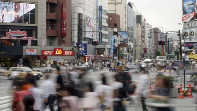 imagem desfocada mostra o movimento de pedestres e carros no centro de Tóquio, Japão