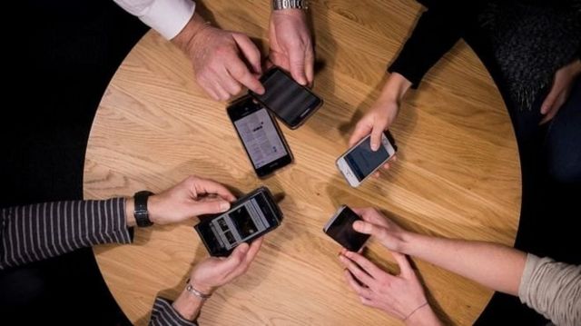 모여 앉아 휴대폰을 보고 있는 사람들