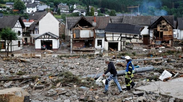 A man and a firefighter walk among the rubble after heavy rain in Szold, Germany