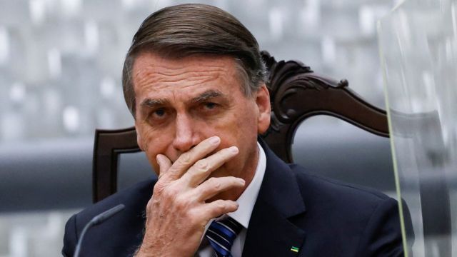 Bolsonaro sentado em sala do Superior Tribunal de Justiça, com mão na boca e expressão fechada