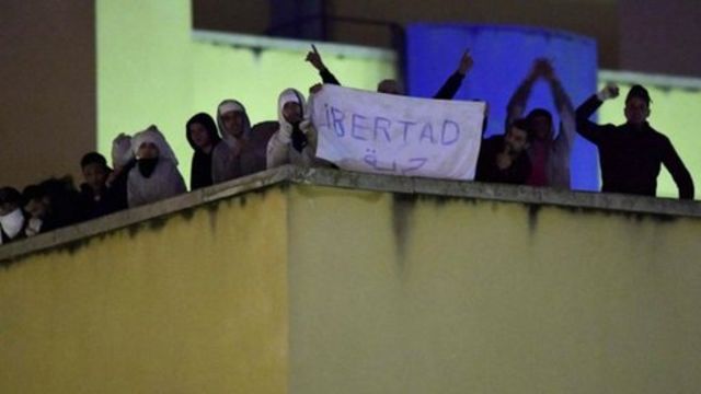 Internos en la azotea del centro de internamiento de extranjeros en Aluche, Madrid, con una pancarta que reza "libertad"